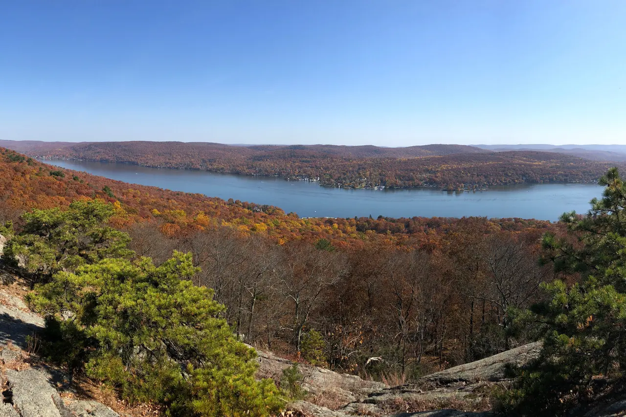 Greenwood Lake seen from a rocky ridge in autumn, with wooded hills on either side
